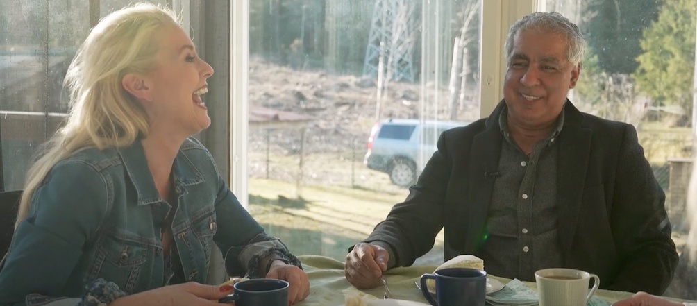 Veckans lyckolats i Ljungbro Två personer sitter vid ett bord med kaffe och bröd framför sig i ett soligt rum med utsikt över en skog.