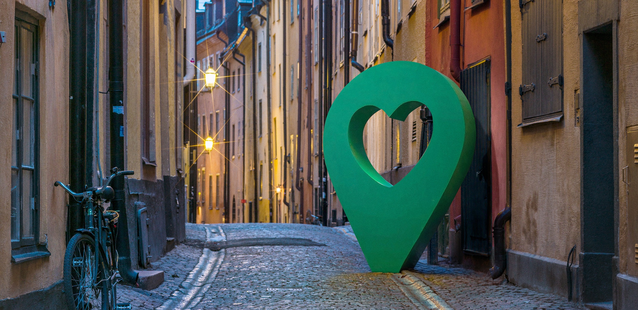 Gamla stan med hjärtpunktmarkör Vacker gata i Gamla stan, Stockholm, med en stor grön hjärtformad punktmarkör längs den kullerstensbelagda vägen.