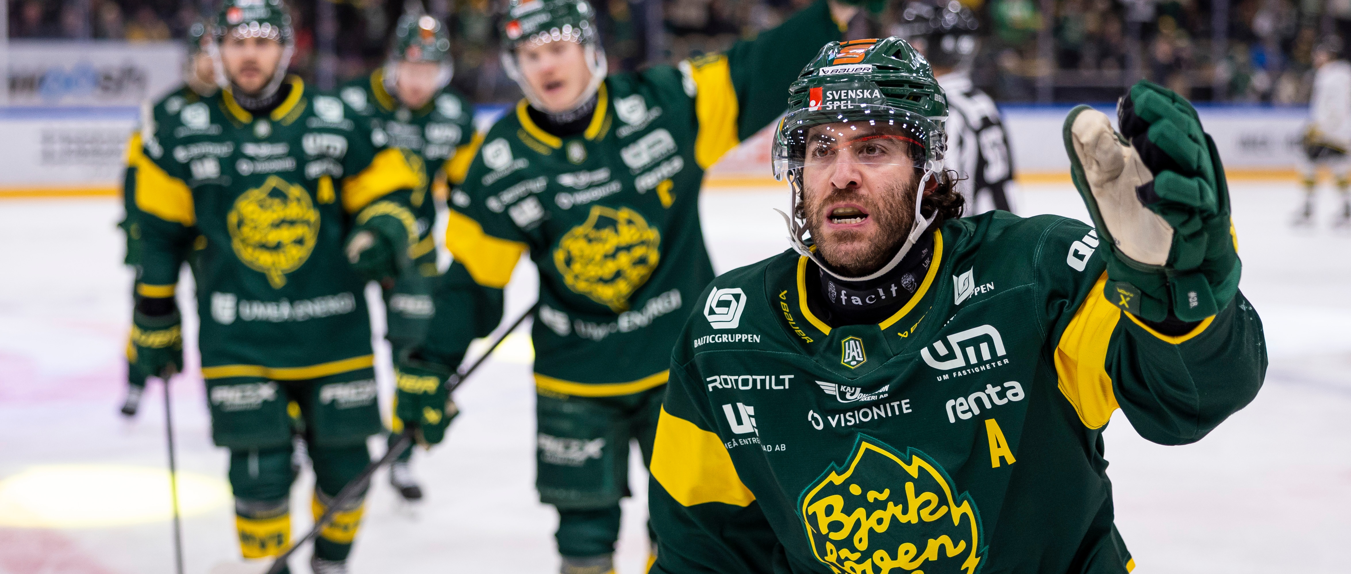 Ishockeylag firar på isen Ishockeyspelare i gröna och gula dräkter firar på isen under en match.