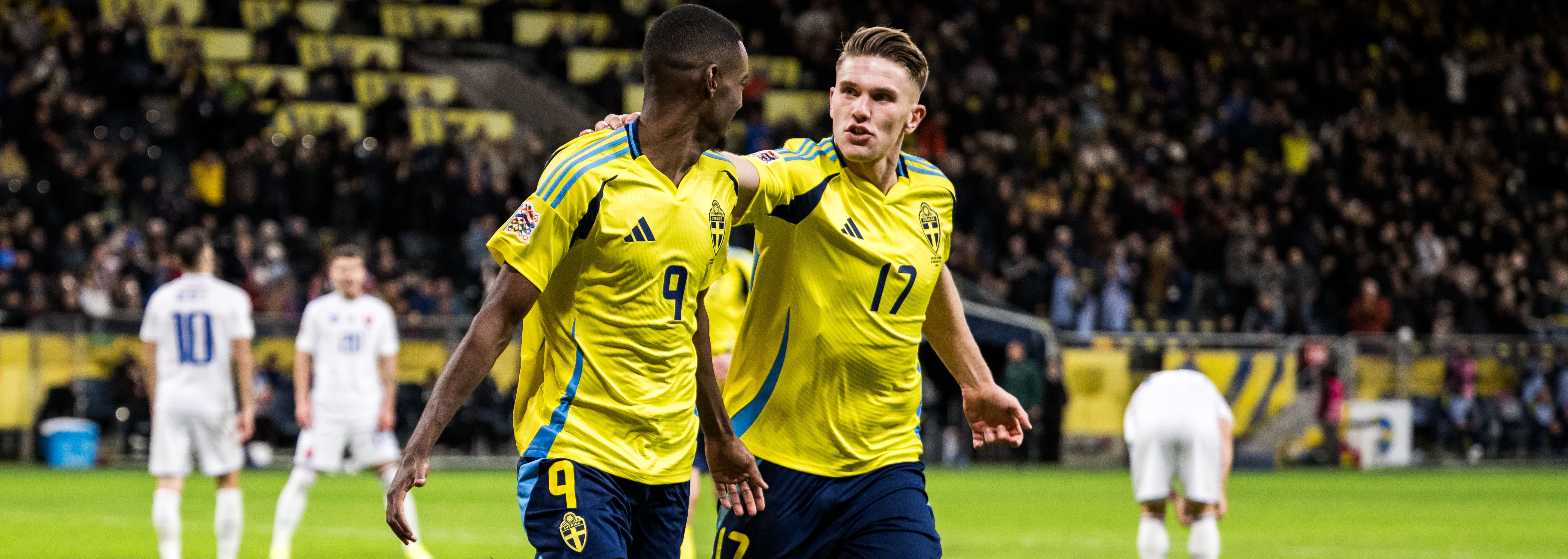 Svenska spelare firar mål Två svenska fotbollsspelare firar ett mål under VM-kvalmatchen mot ett annat landslag.