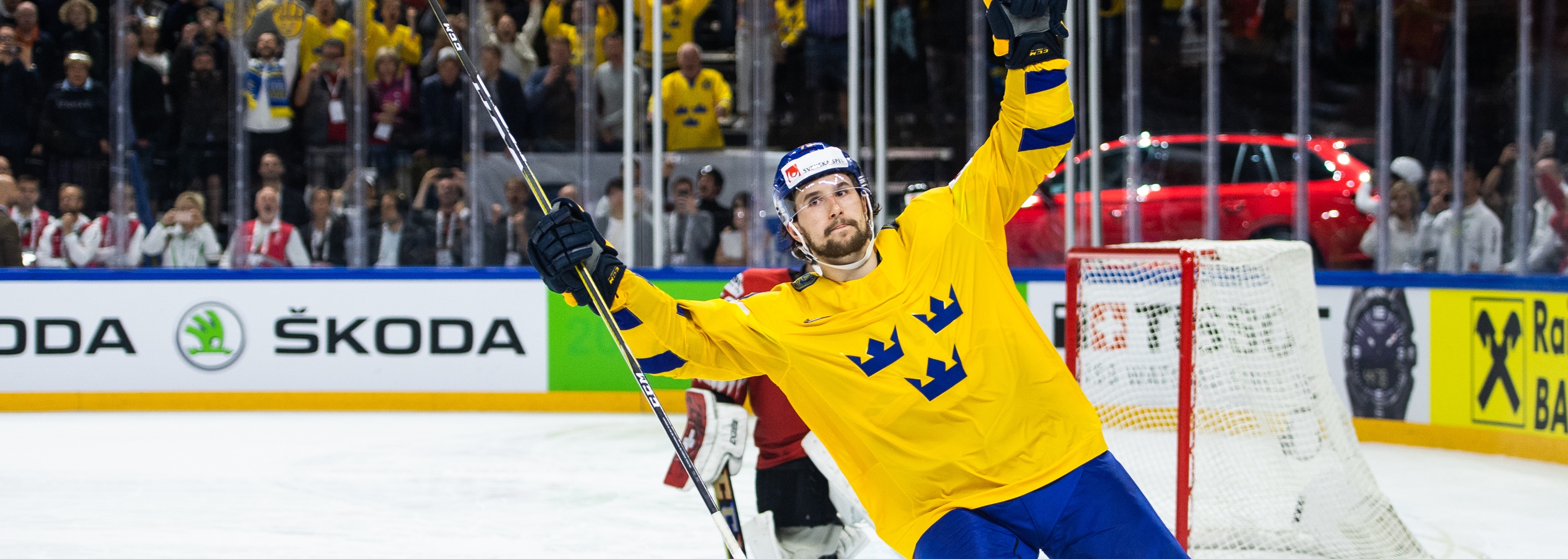 Tre Kronor målfirande En ivrig ishockeyspelare i Tre Kronor-tröja firar med publiken efter att ha gjort ett mål.
