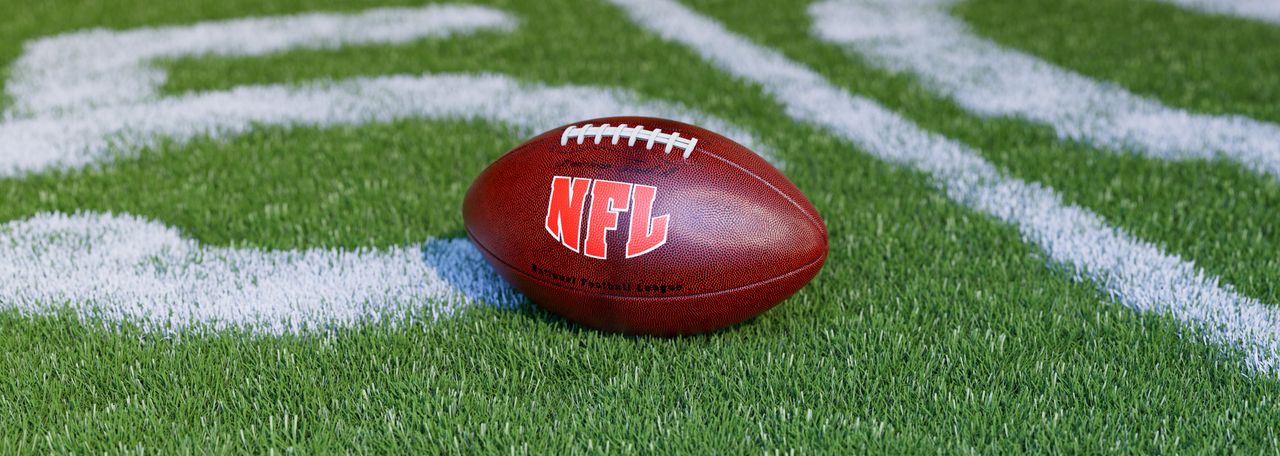 NFL-amerikansk fotboll på en grönt gräsplan, i närheten av mittfältets 50-yards linje.