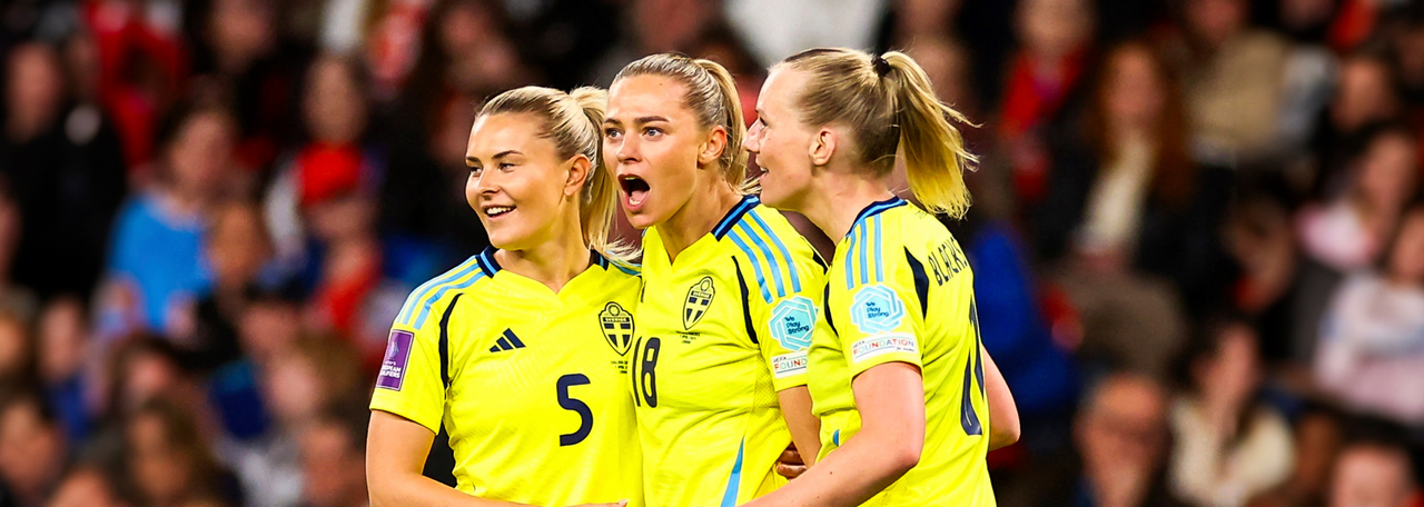 Svenska damlandslaget i fotboll spelar en match under EM 2025. Spelarna bär gula tröjor med blå detaljer.