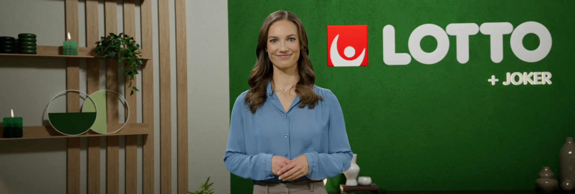 Person i blå skjorta står framför en grön bakgrund med Lotto-logotypen synlig.