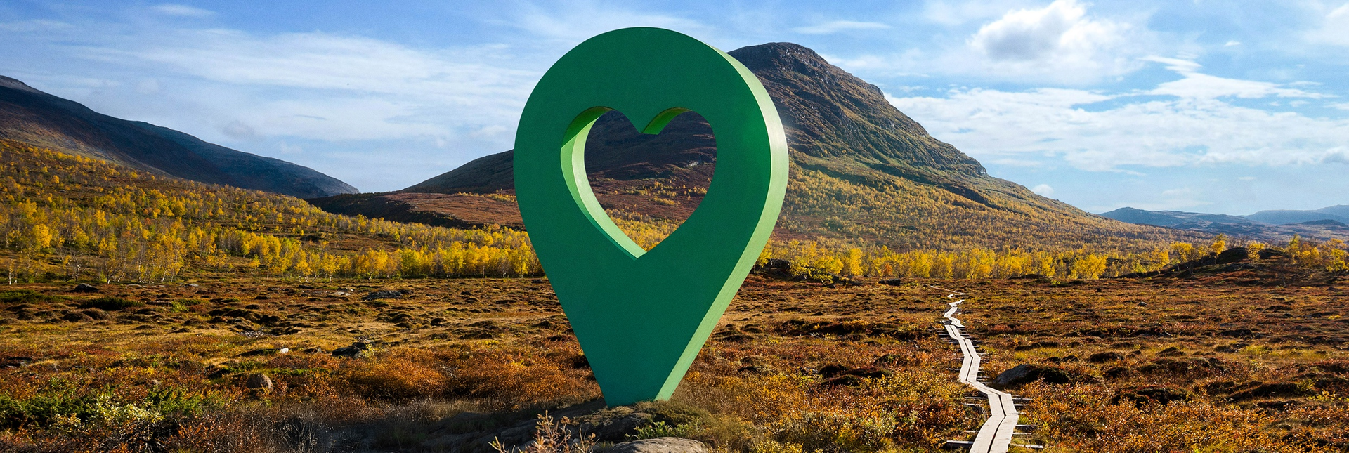 Bild av Lyckplatsen med en stor grön hjärtformad platsmarkering i ett vackert landskap under blå himmel.