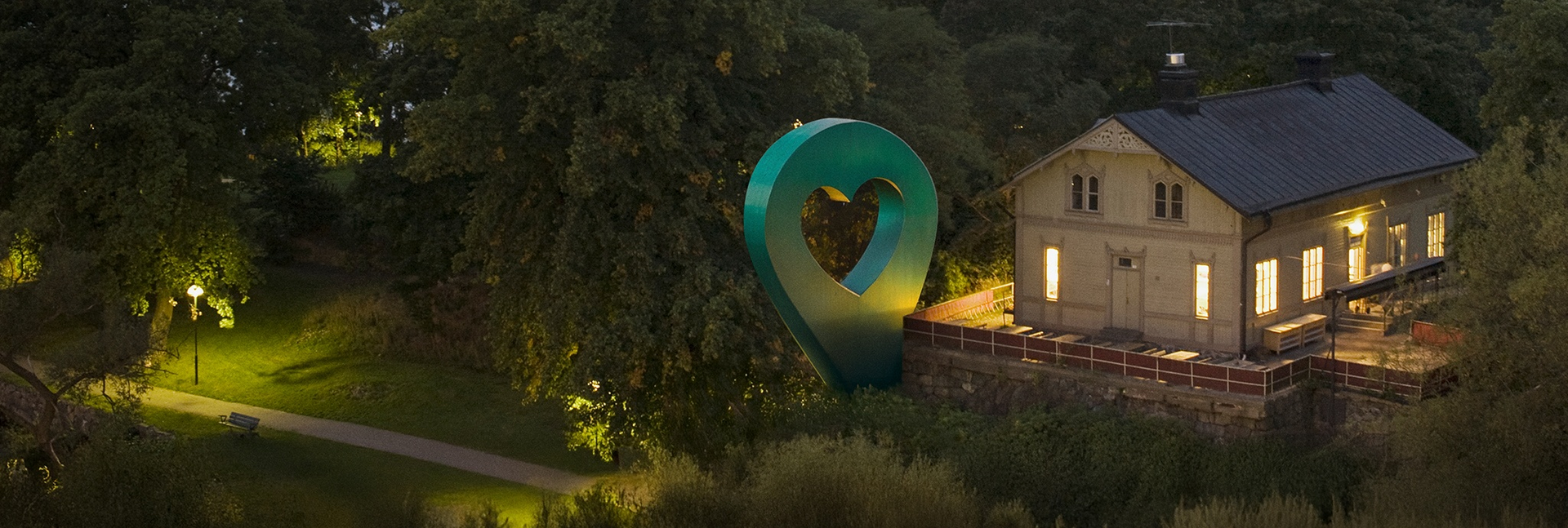 Bild av Lyckplatsen som visar ett hus med ett hjärtaformad skulptur.