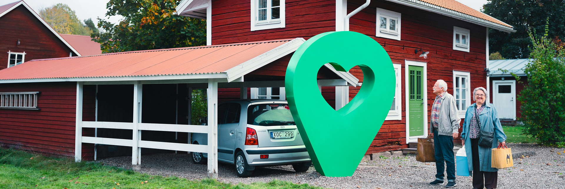 Ett rött sommarhus med carport och två glada personer. En grön pin med hjärta är placerad vid huset.