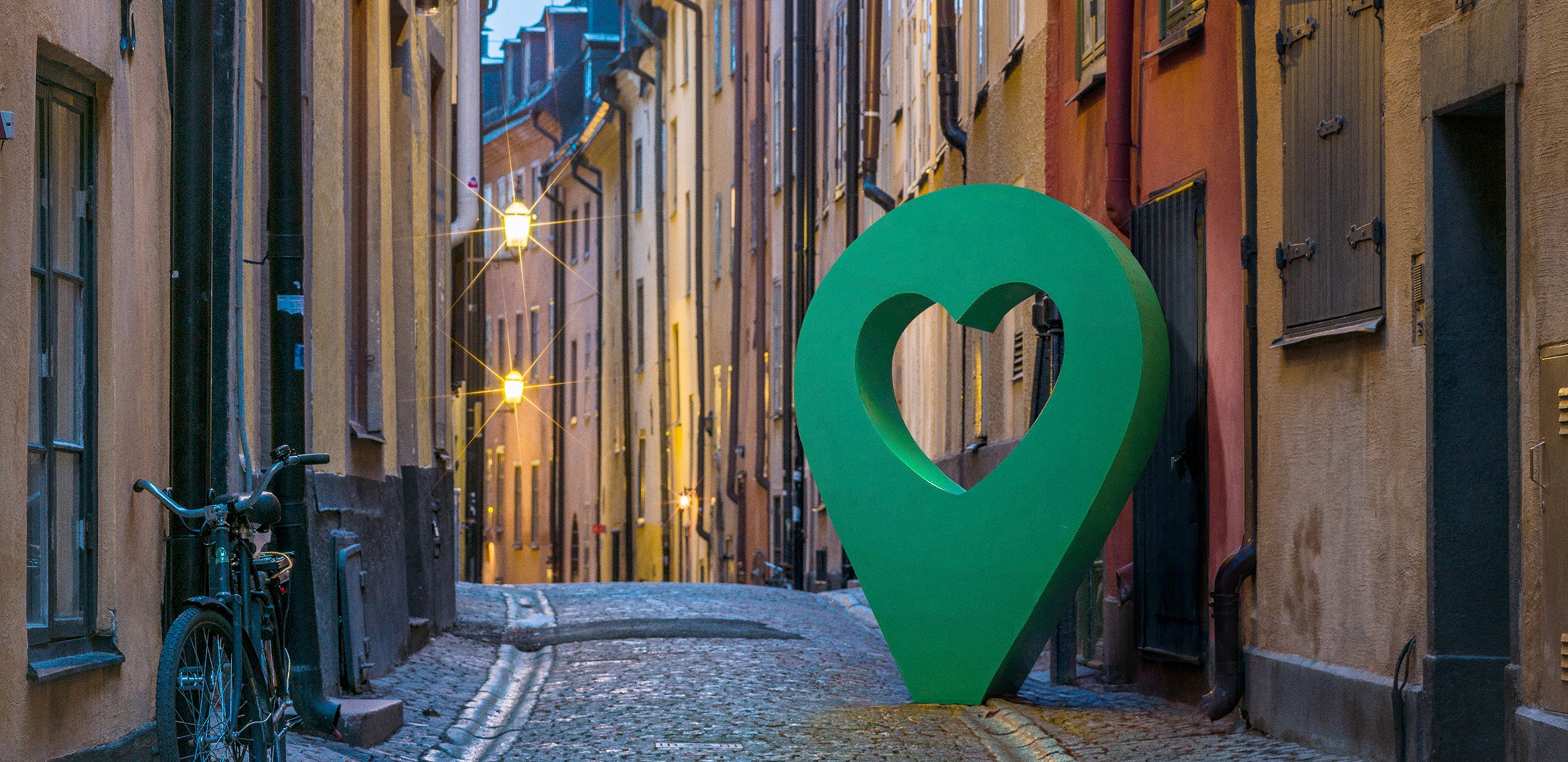 Vacker gata i Gamla stan, Stockholm, med en stor grön hjärtformad punktmarkör längs den kullerstensbelagda vägen.