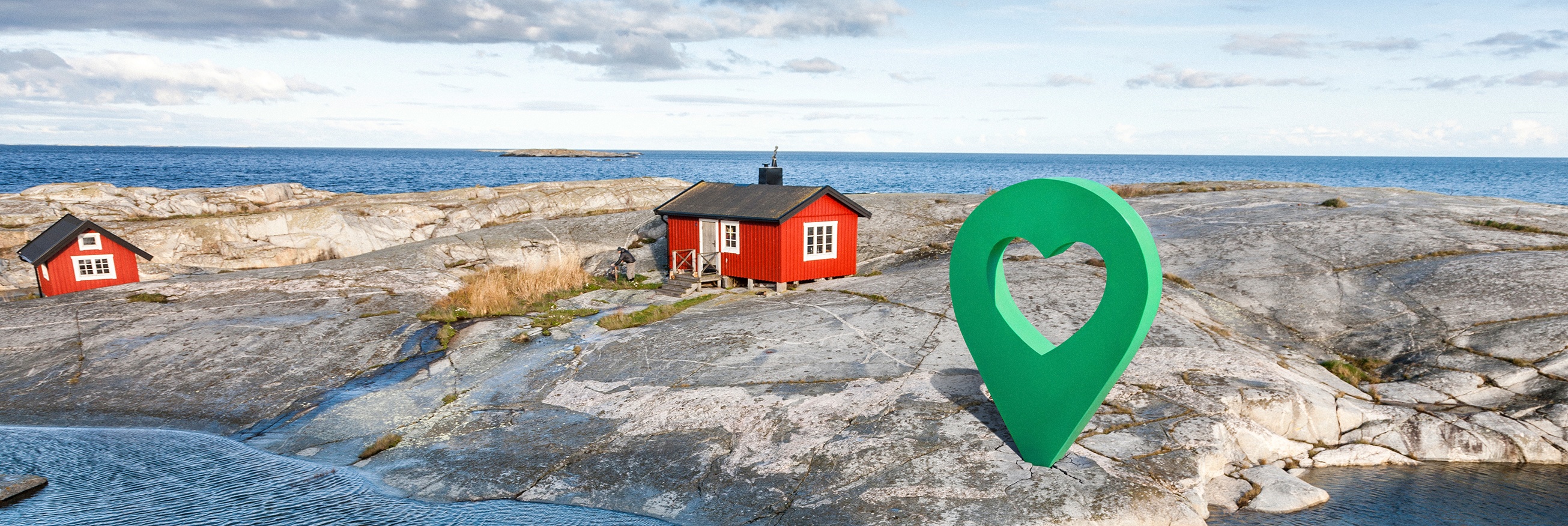 Person paddlar kajak vid klippor med röda stugor och en grön platsmarkör med hjärtsymbol nära Lyckplatsen.