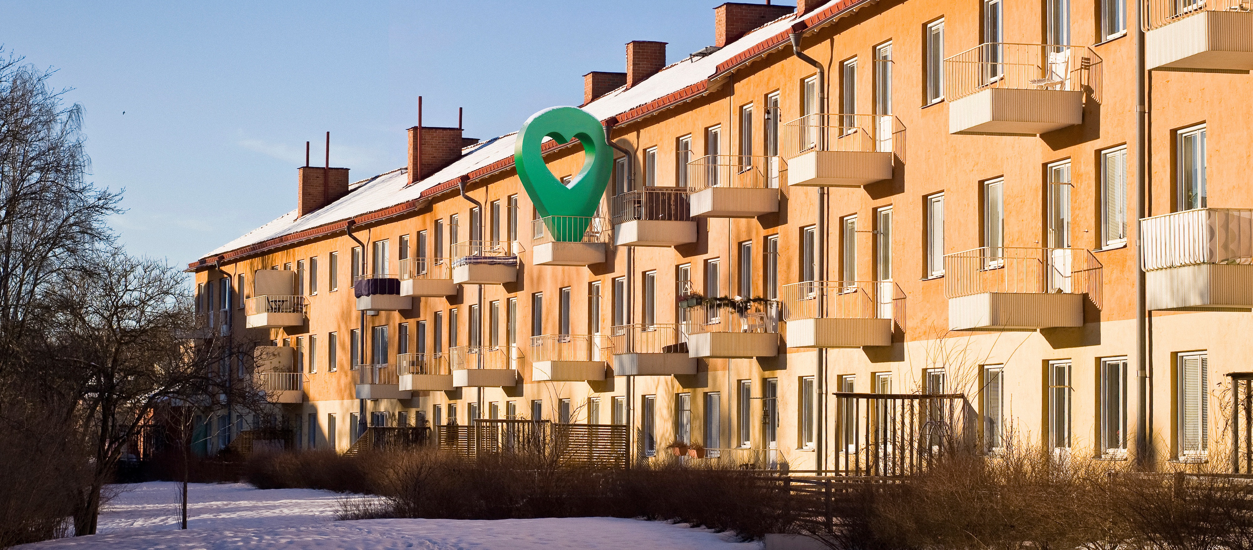 Lägenhetshus i vintermiljö med snöklädd mark och klarblå himmel.