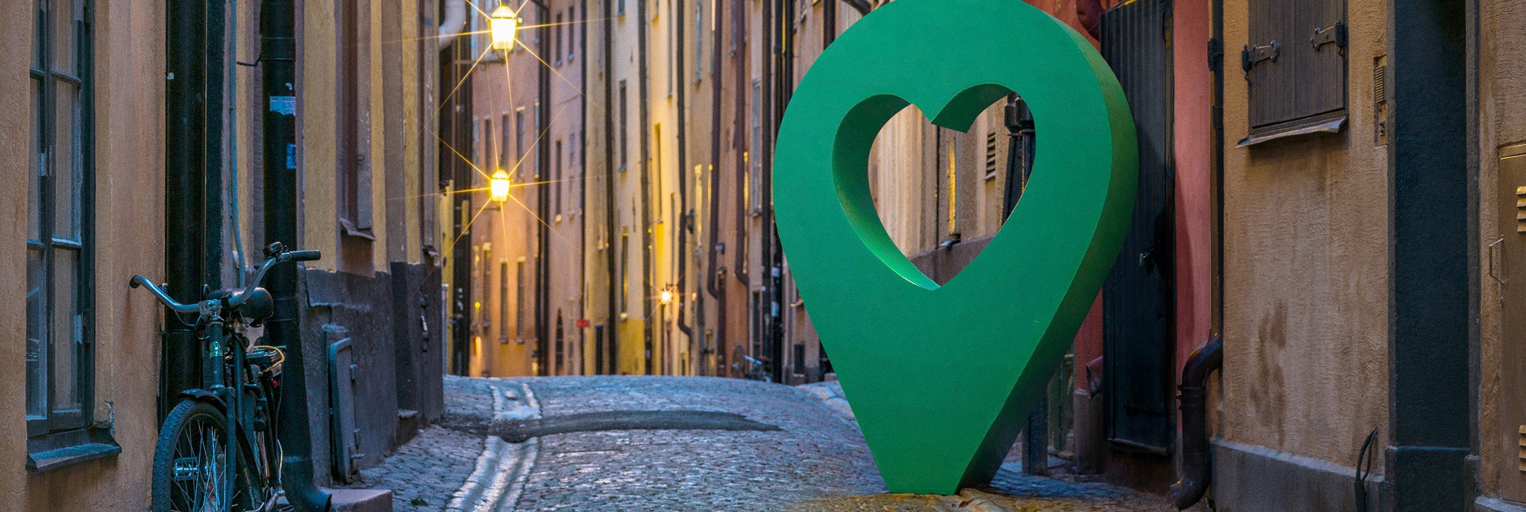 Vacker gata med en stor grön hjärtformad punktmarkör längs den kullerstensbelagda vägen.