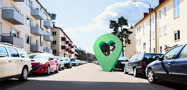 Lyckplatsen symbol på en solig bostadsgata med parkerade bilar och flerfamiljshus.