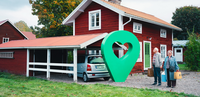 Ett rött sommarhus med carport och två glada personer. En grön pin med hjärta är placerad vid huset.