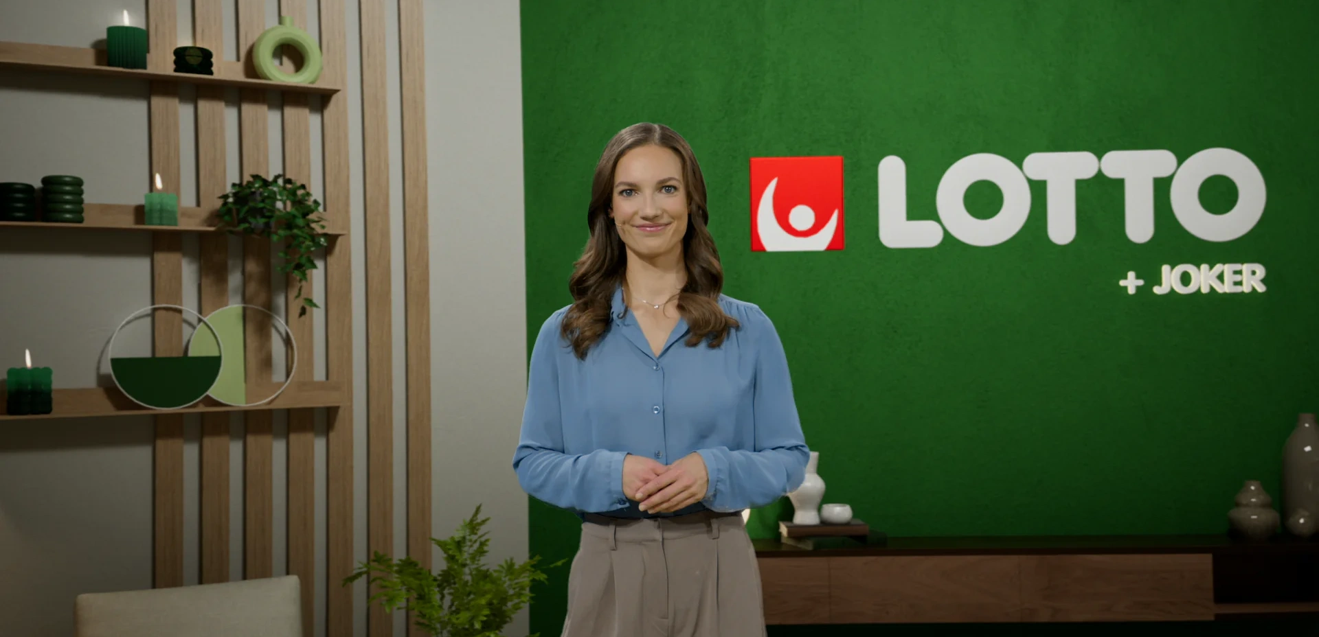 Person i blå skjorta står framför en grön bakgrund med Lotto-logotypen synlig.