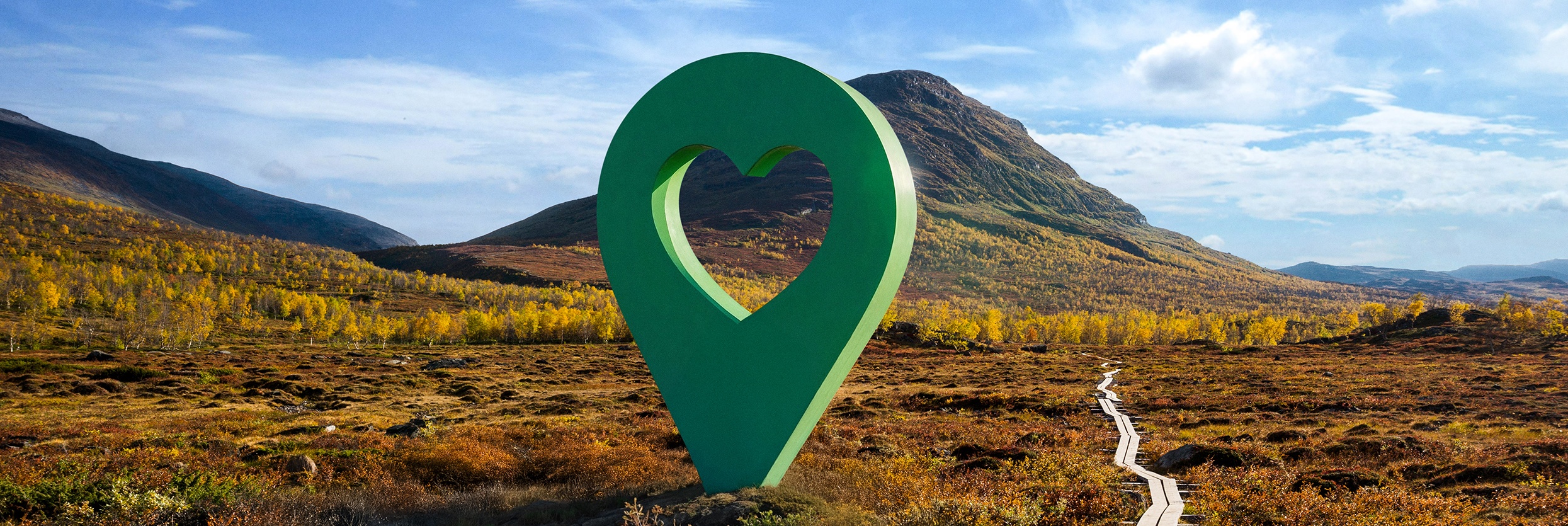 Bild av Lyckplatsen med en stor grön hjärtformad platsmarkering i ett vackert landskap under blå himmel.