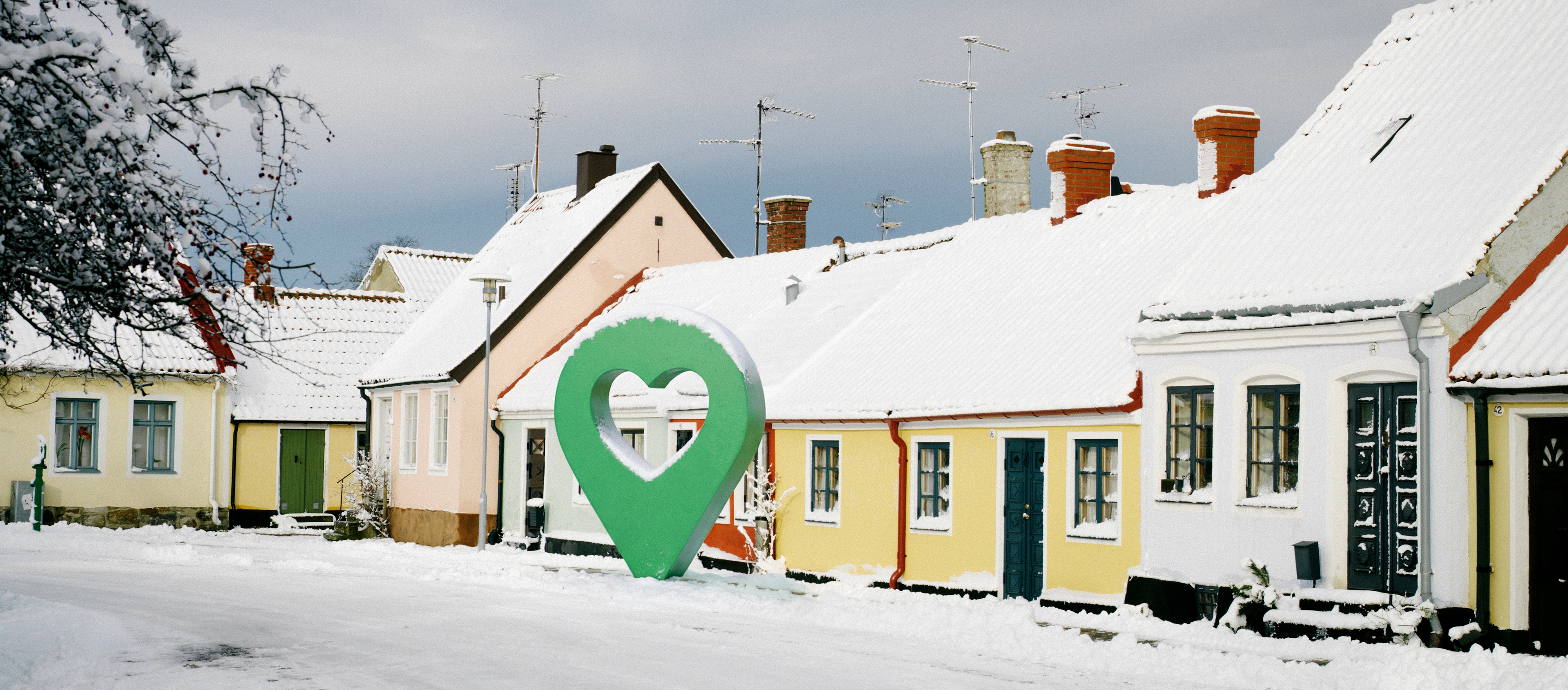 Snötäckt gata med pittoreska hus och en grön markörformad symbol i mitten.