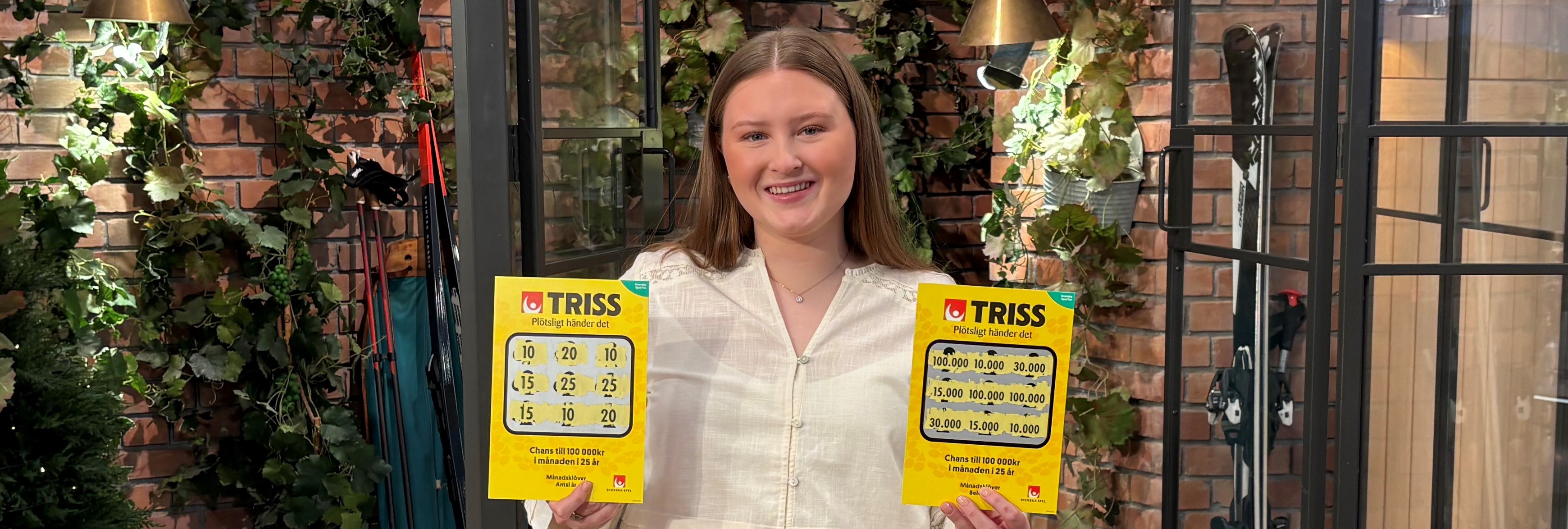 Person håller två Trisslotter och står i en inglasad trädgårdsmiljö med växter i bakgrunden.