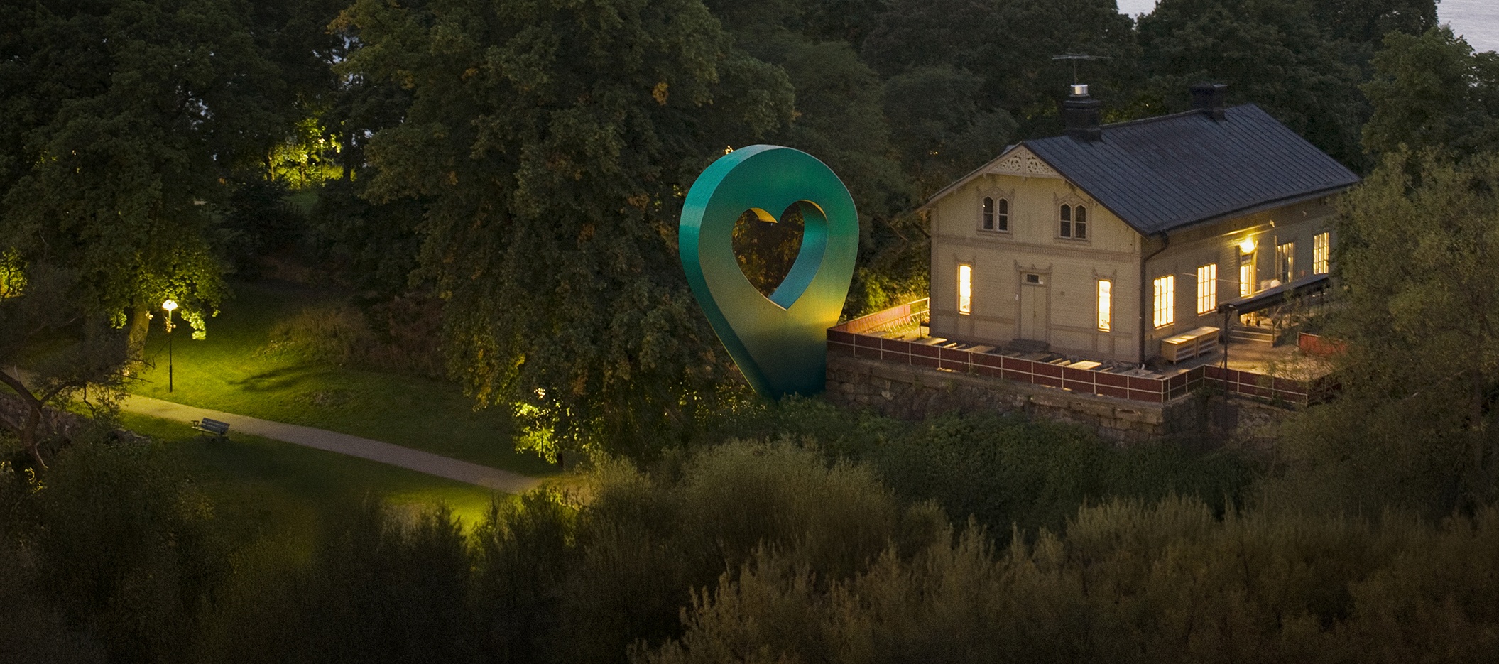 Bild av Lyckplatsen som visar ett hus med ett hjärtaformad skulptur.