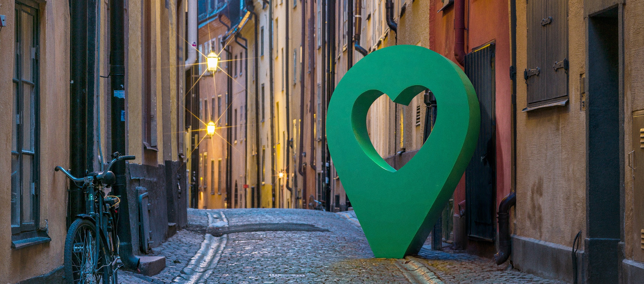 Vacker gata i Gamla stan, Stockholm, med en stor grön hjärtformad punktmarkör längs den kullerstensbelagda vägen.