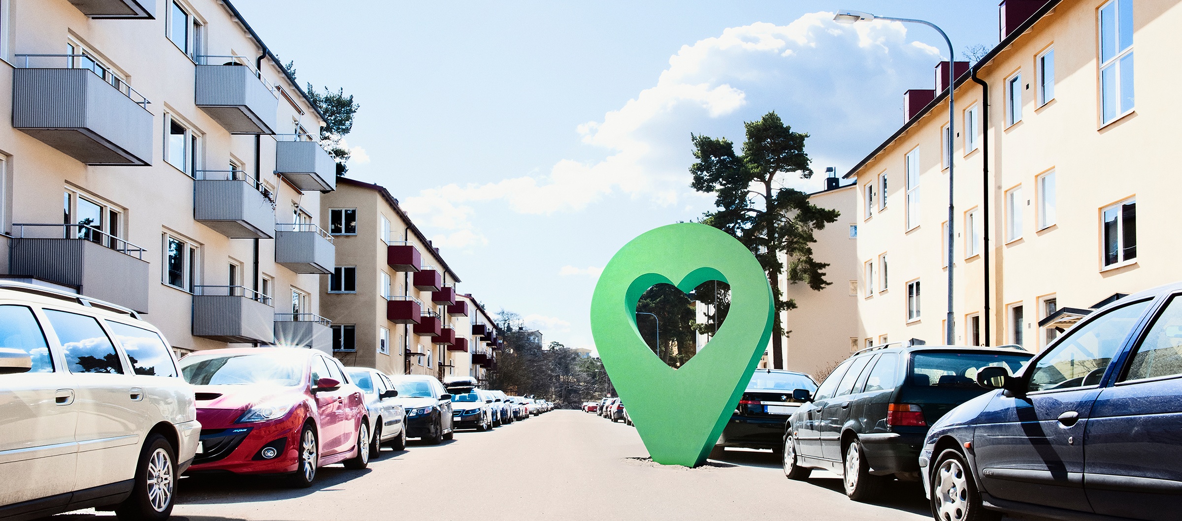 Lyckoplatsen symbol på en solig bostadsgata med parkerade bilar och flerfamiljshus.
