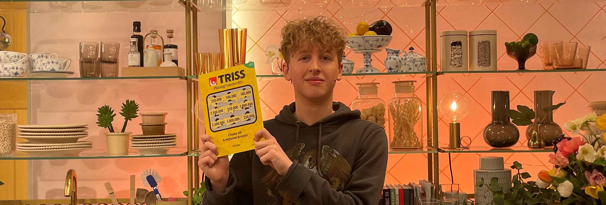 Trissvinnaren Gustav från Bromma håller upp sin vinnarlott i tv-studion