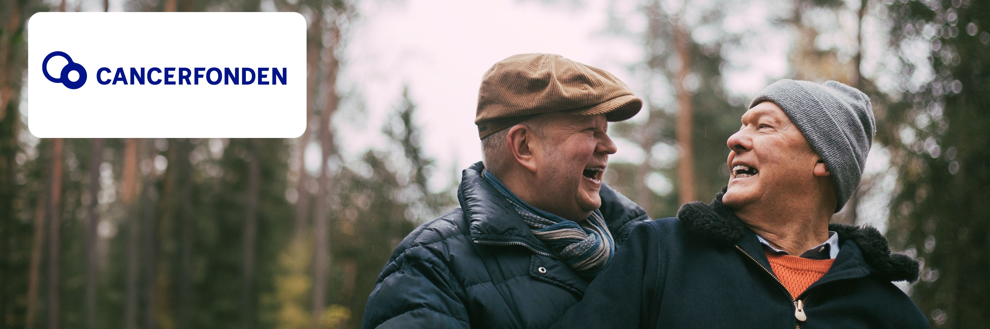 Två glada män i skogsmiljö med Cancerfonden-logotypen synlig i bilden.