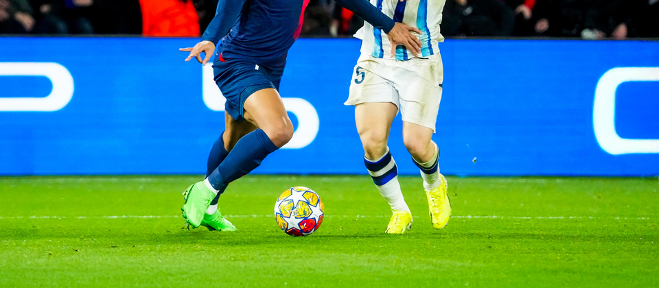 Två fotbollsspelare tävlar om bollen under en Champions League-match, omgivna av åskådare.
