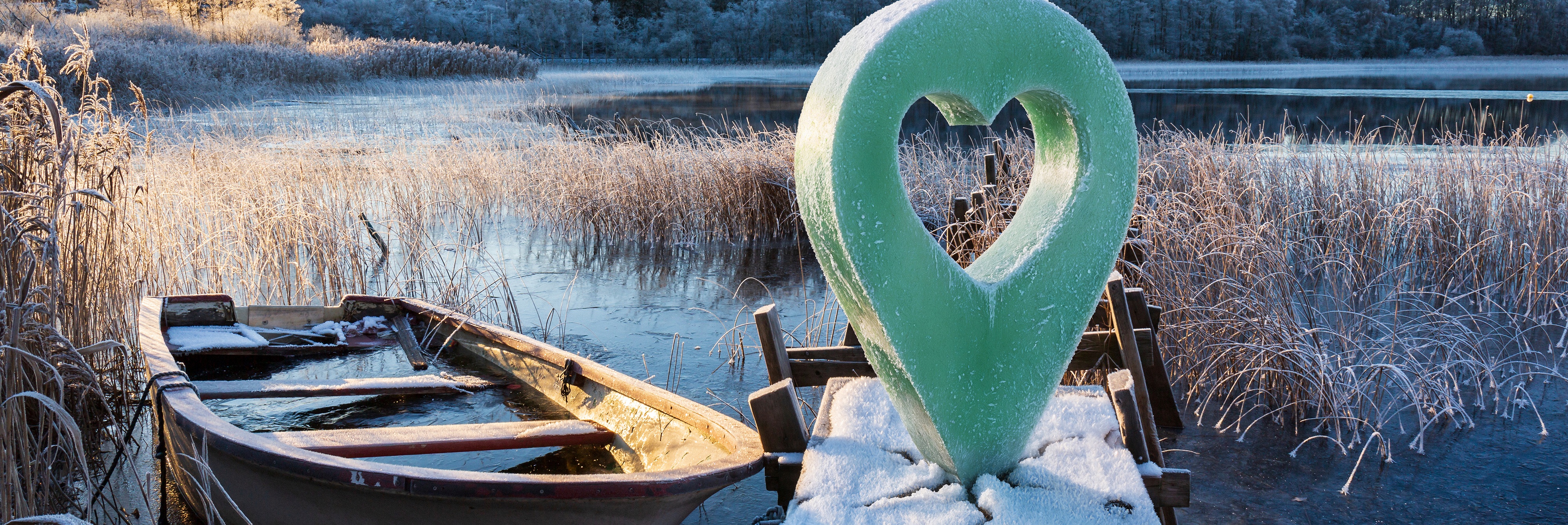 Frostig brygga med båt vid vinterlandskap och en markör med hjärta.