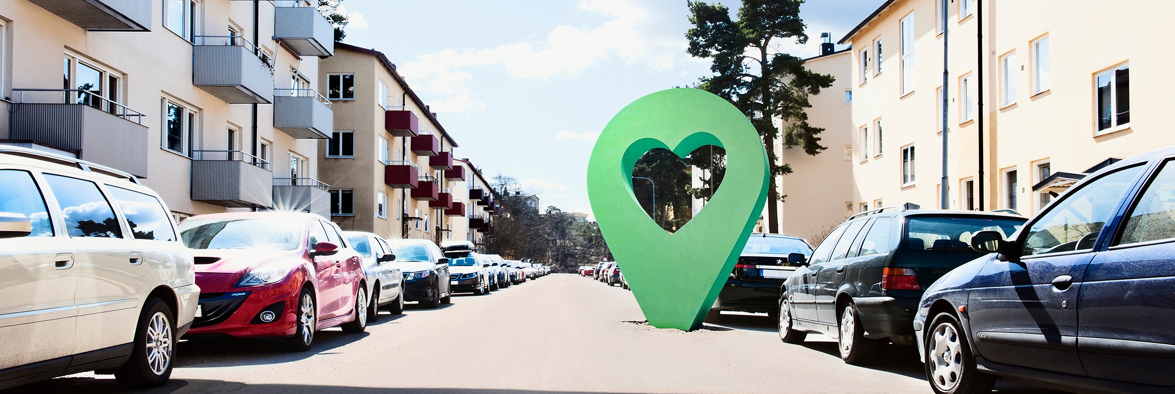 Lyckplatsen symbol på en solig bostadsgata med parkerade bilar och flerfamiljshus.