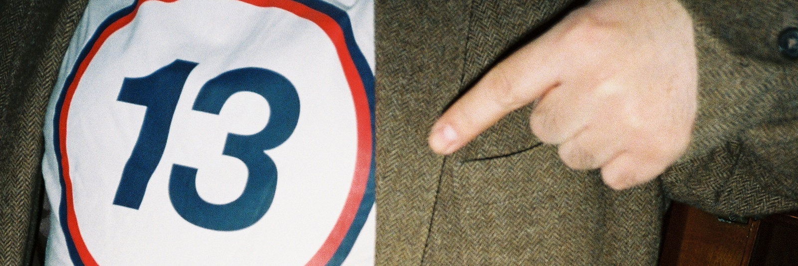 En närbild av en person som pekar på en tröja med siffran 13 i en cirkel.