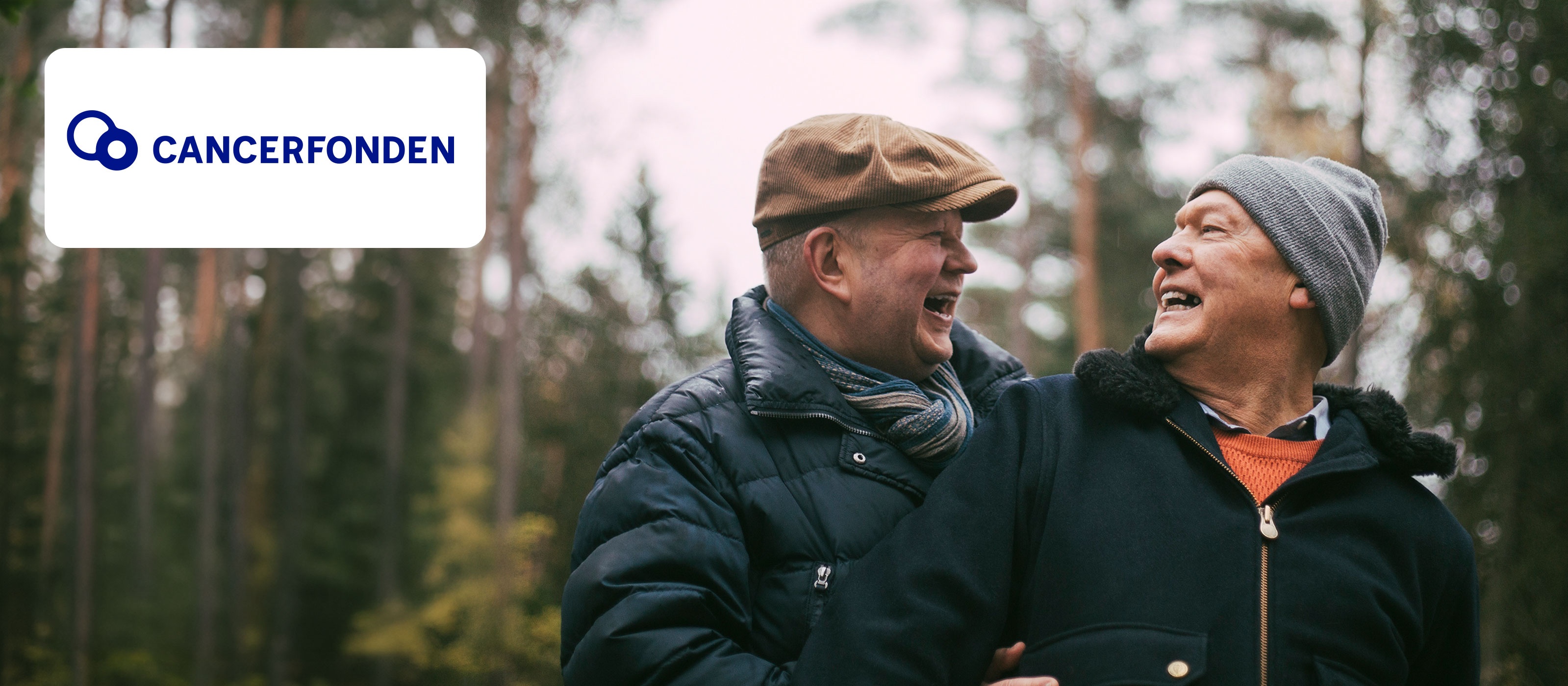 Två glada män i skogsmiljö med Cancerfonden-logotypen synlig i bilden.