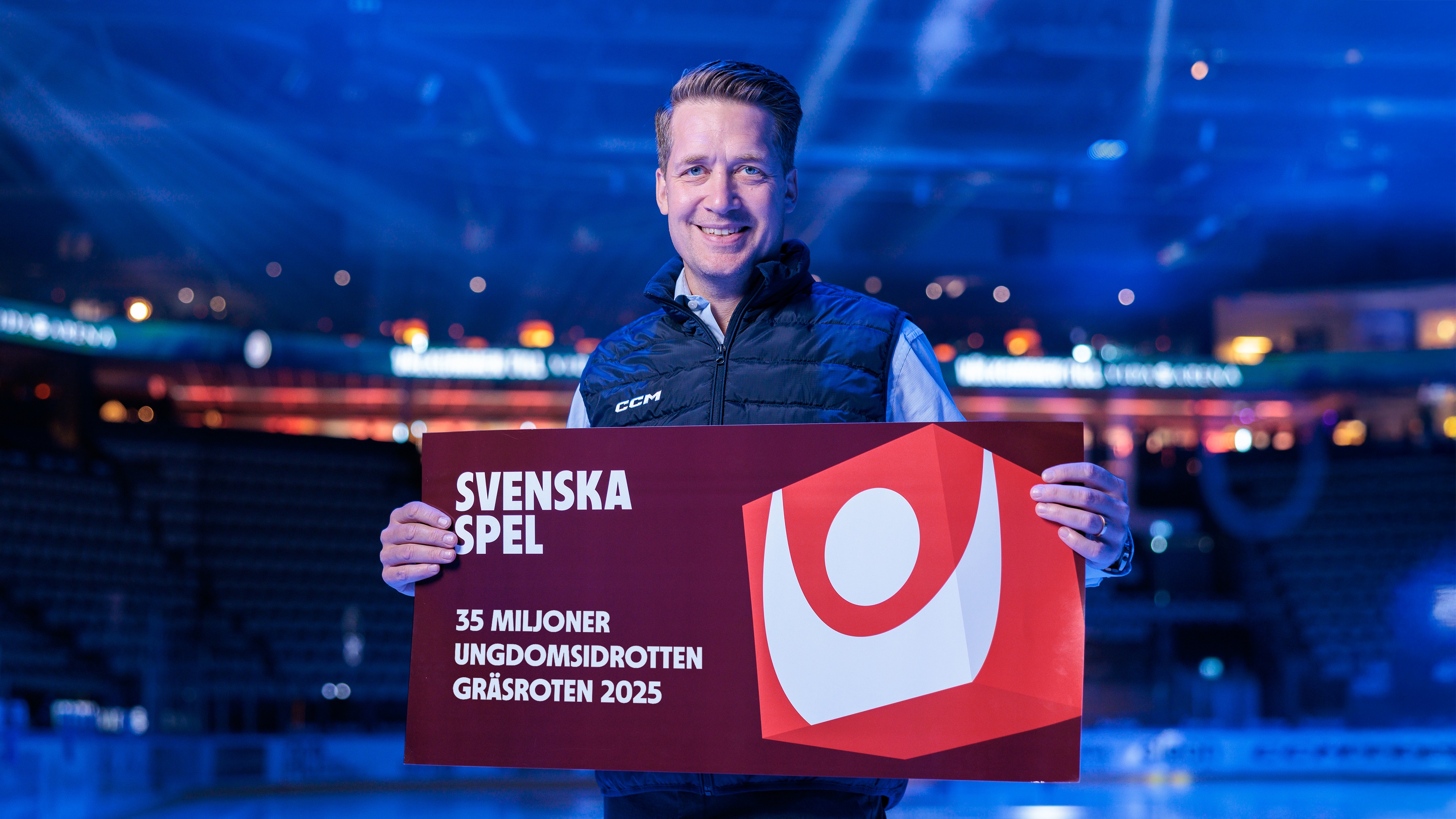 Sam Hallam håller en skylt som visar Svenska Spel och Gräsroten 35 miljoner till ungdomsidrott.