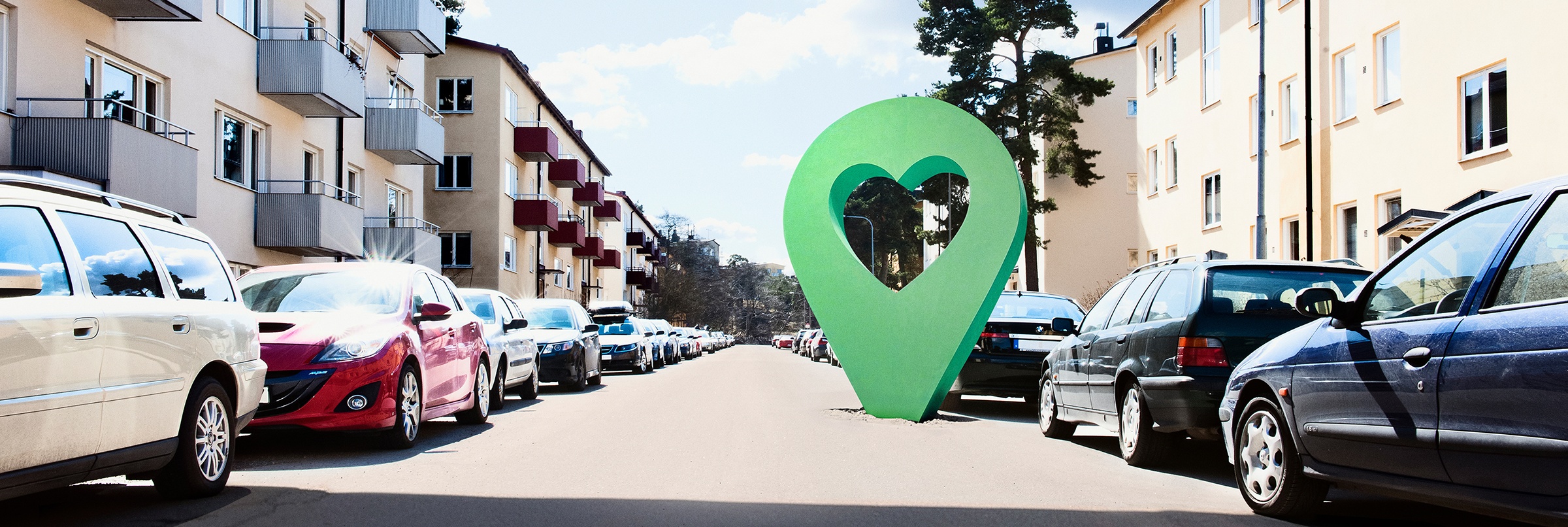 Lyckplatsen symbol på en solig bostadsgata med parkerade bilar och flerfamiljshus.