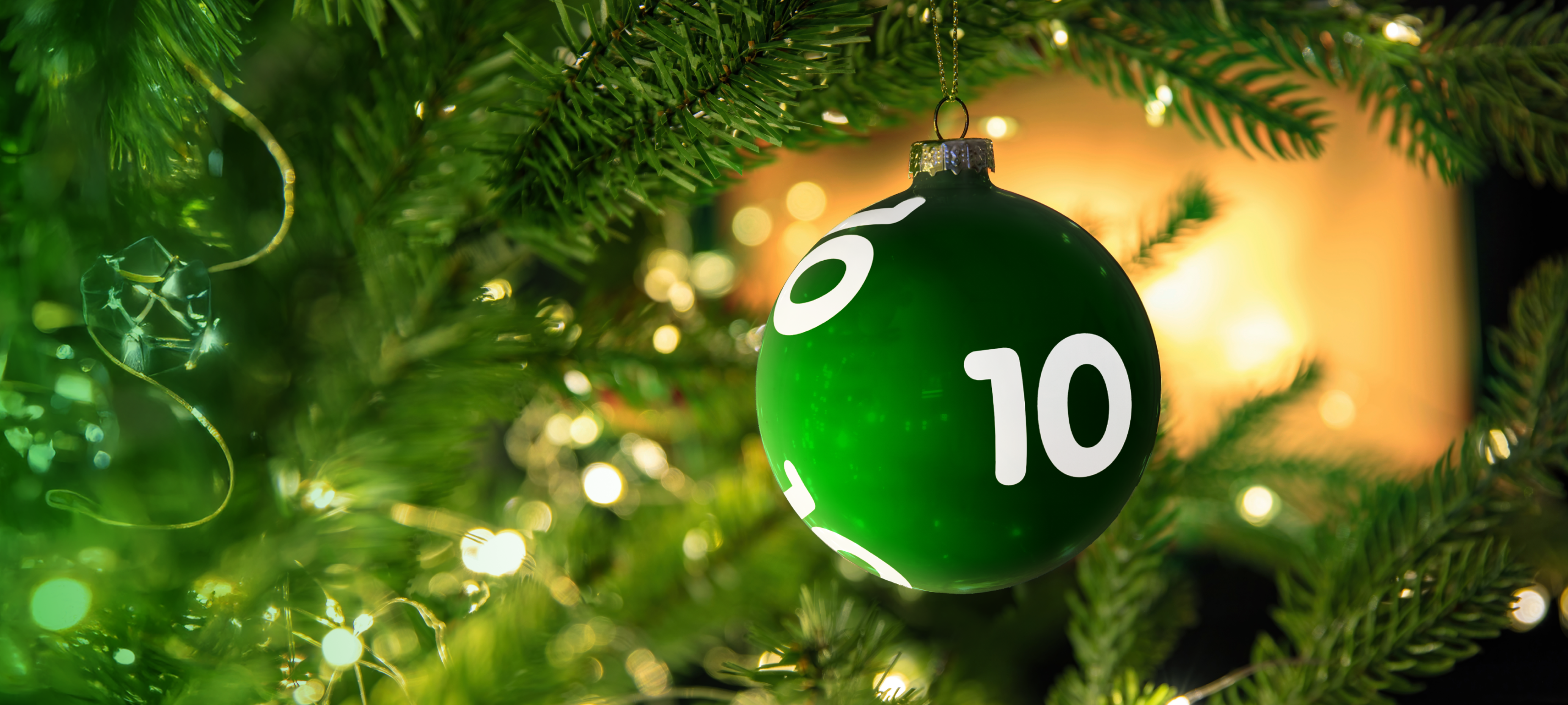 En juldekoration i form av en grön lottoboll med siffran 10 hänger i en julgran.