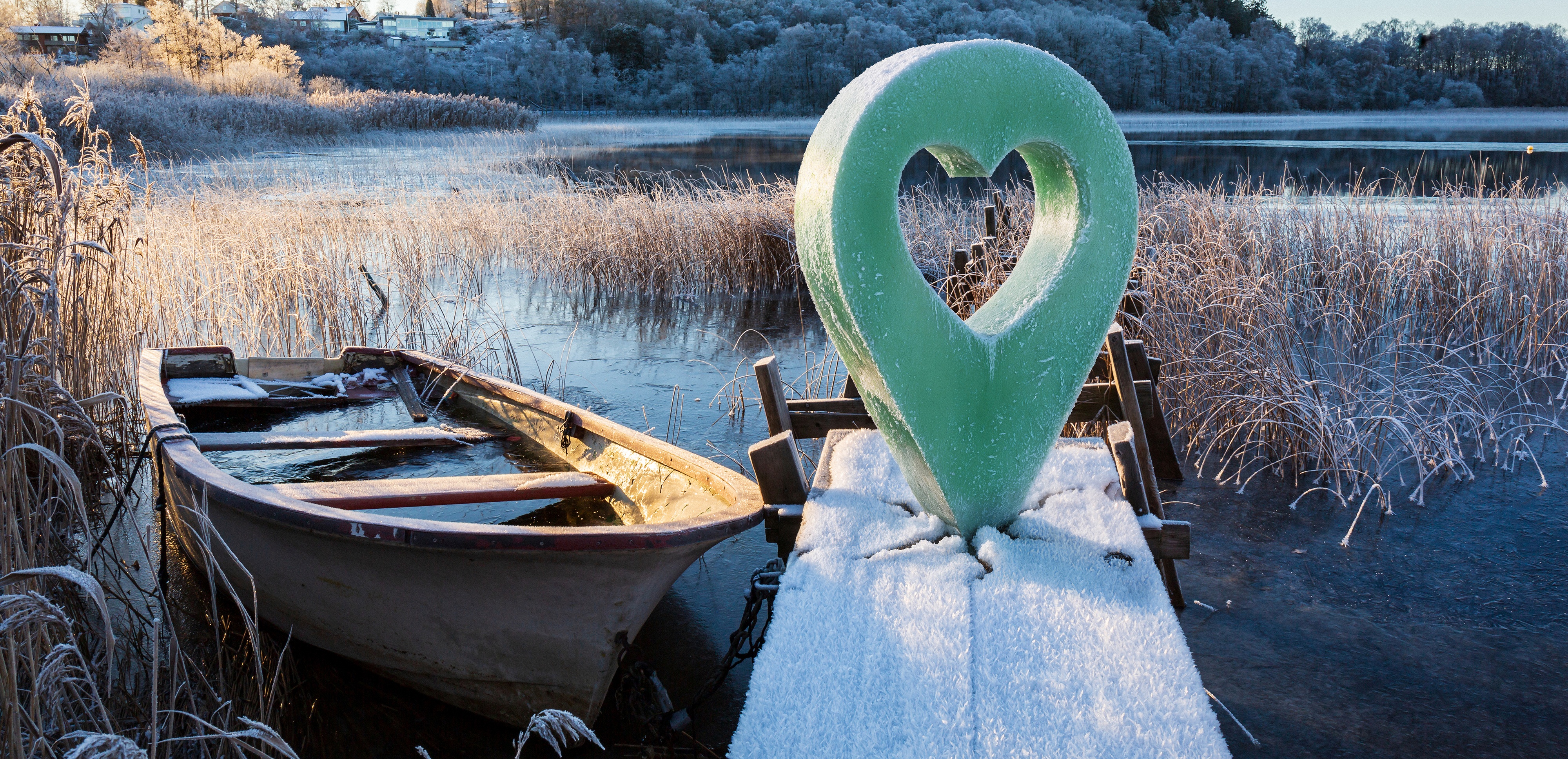 Frostig brygga med båt vid vinterlandskap och en markör med hjärta.