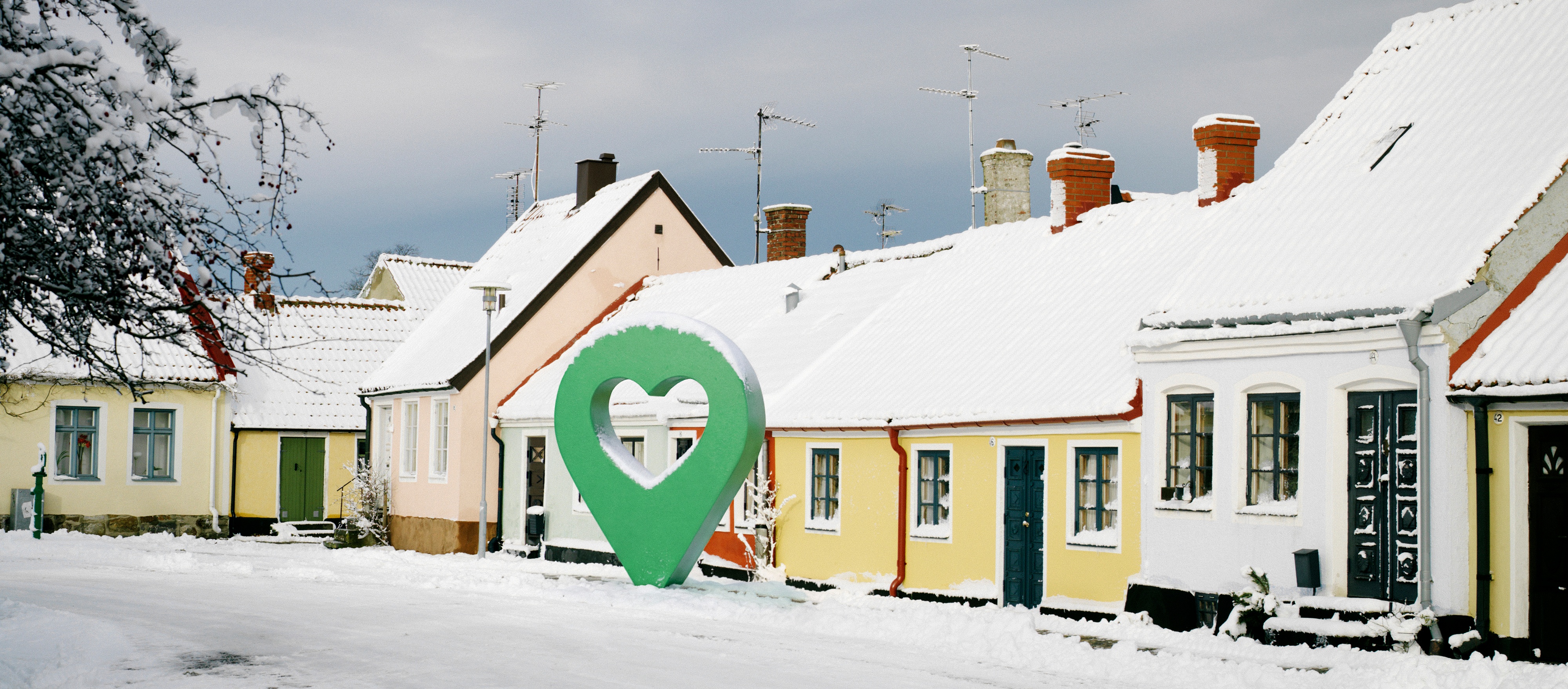Snötäckt gata med pittoreska hus och en grön markörformad symbol i mitten.